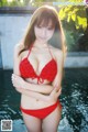 A woman in a red bikini posing by a pool.