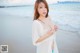 A woman in a white dress standing on a beach.