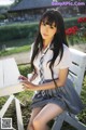 A woman in a school uniform sitting on a bench.