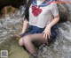 A woman in a sailor outfit is sitting in the water.