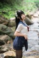 A woman in a school uniform standing in a stream.