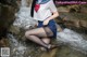 A woman in a school uniform is sitting in a stream.