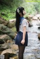 A woman in a school uniform standing in a stream.