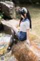 A woman sitting on a rock in the water.