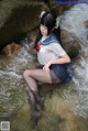 A woman in a sailor outfit is sitting in the water.