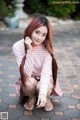 A woman with long red hair sitting on the ground.