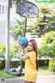 A woman holding a basketball in front of a basketball hoop.