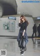 A woman in a black shirt and plaid skirt is walking through an airport.