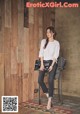 A woman sitting on a chair in front of a wooden wall.