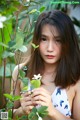 A young woman holding a white flower in her hand.