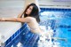 A woman in a white bikini sitting in a swimming pool.