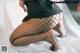 A woman in fishnet stockings is sitting on a bed.