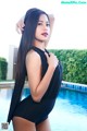 A woman in a black bathing suit standing next to a pool.