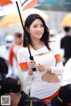 A woman in a white and orange outfit holding an umbrella.