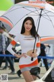 A woman in a white and orange dress holding an umbrella.