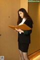 A woman in a business suit holding a folder.