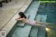 A woman in a pink bikini laying on the edge of a swimming pool.