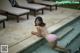 A woman in a pink bikini sitting on the edge of a pool.