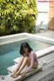 A woman sitting on the edge of a swimming pool.