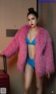 A woman in a blue bikini and a pink fur coat.