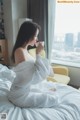 A woman sitting on a bed holding a cup of coffee.