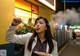 A woman holding a plate of food with chopsticks in her mouth.