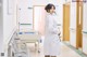 A woman in a white lab coat standing in a hospital hallway.