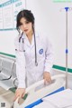 A woman in a white lab coat standing next to a hospital bed.