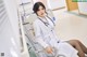 A woman in a white lab coat sitting on a chair.