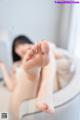 A woman is sitting in a bathtub with her feet up.