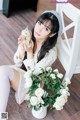 A woman sitting on the floor holding a vase of flowers.