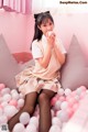 A woman sitting on top of a bed covered in pink and white balloons.