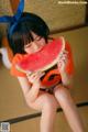 A woman sitting on the floor eating a slice of watermelon.