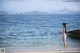 A woman in a white bikini standing in the water.