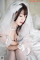 A woman in a wedding dress sitting on a bed.