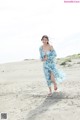 A woman in a blue dress running on a sandy beach.