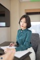 A woman sitting at a desk writing on a piece of paper.