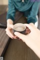 A woman holding a cup of coffee on a table.