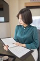 A woman sitting at a table writing in a notebook.