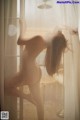 A naked woman standing in front of a window.