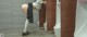 A woman in a school uniform leaning against a urinal.