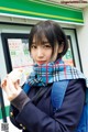 A woman in a school uniform eating a sandwich.