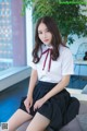 A woman in a white shirt and black skirt sitting on a couch.