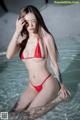 A woman in a red bikini sitting in a pool.