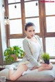 A woman sitting on a couch holding a potted plant.