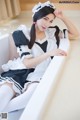 A woman in a maid outfit sitting in a bathtub.