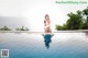 A woman in a red bikini sitting on the edge of a swimming pool.