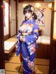 A woman in a blue kimono standing in a room.