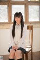 A young woman sitting on a wooden chair in a room.